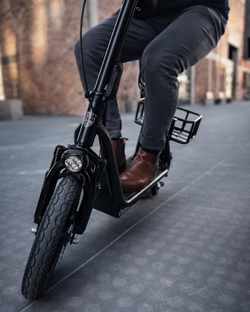 Person riding a black seated electric scooter on a city street.