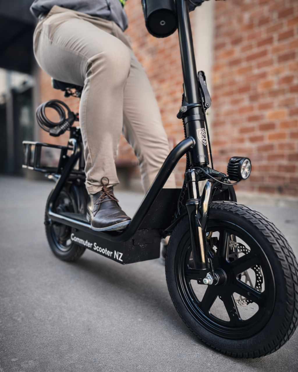 Person riding a black Commuter e-scooter with visible branding on a pavement.