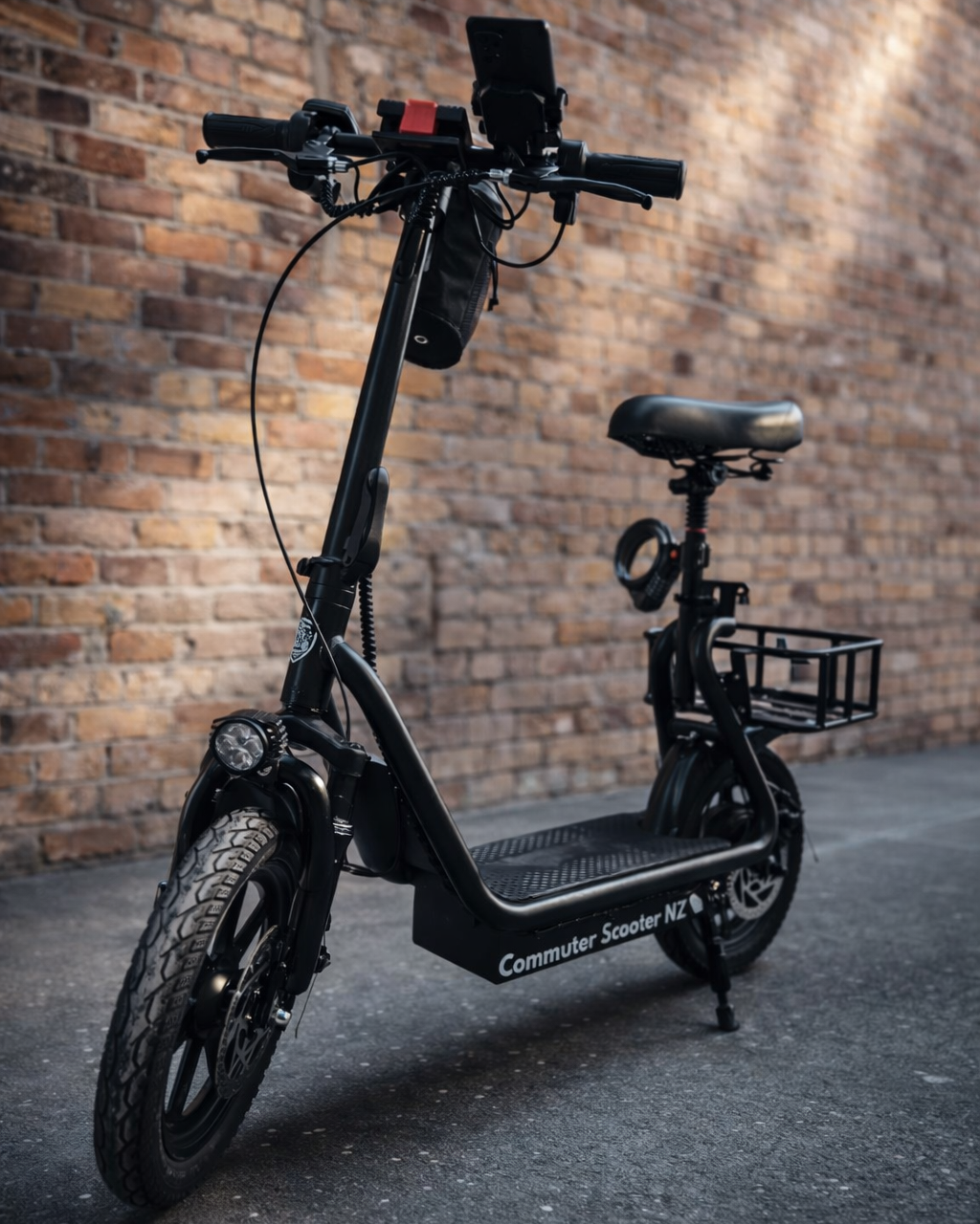 Black electric commuter scooter against a brick wall