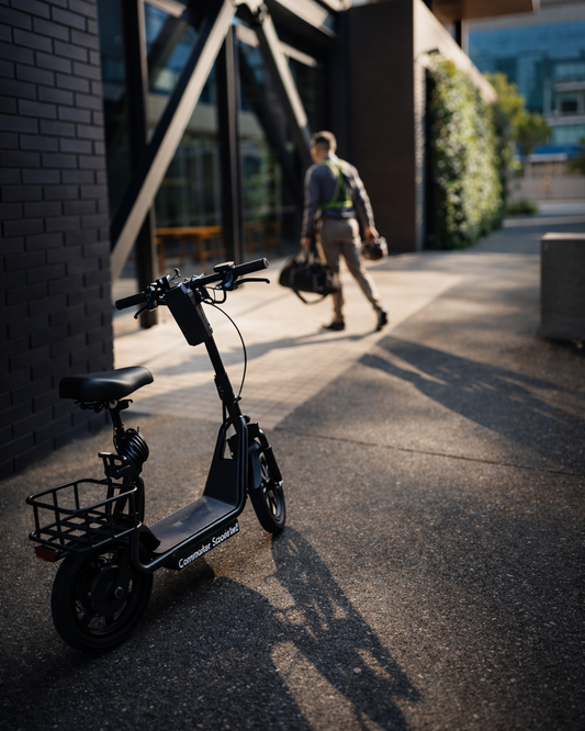 Electric scooter parked on a sidewalk with a person walking in the background.