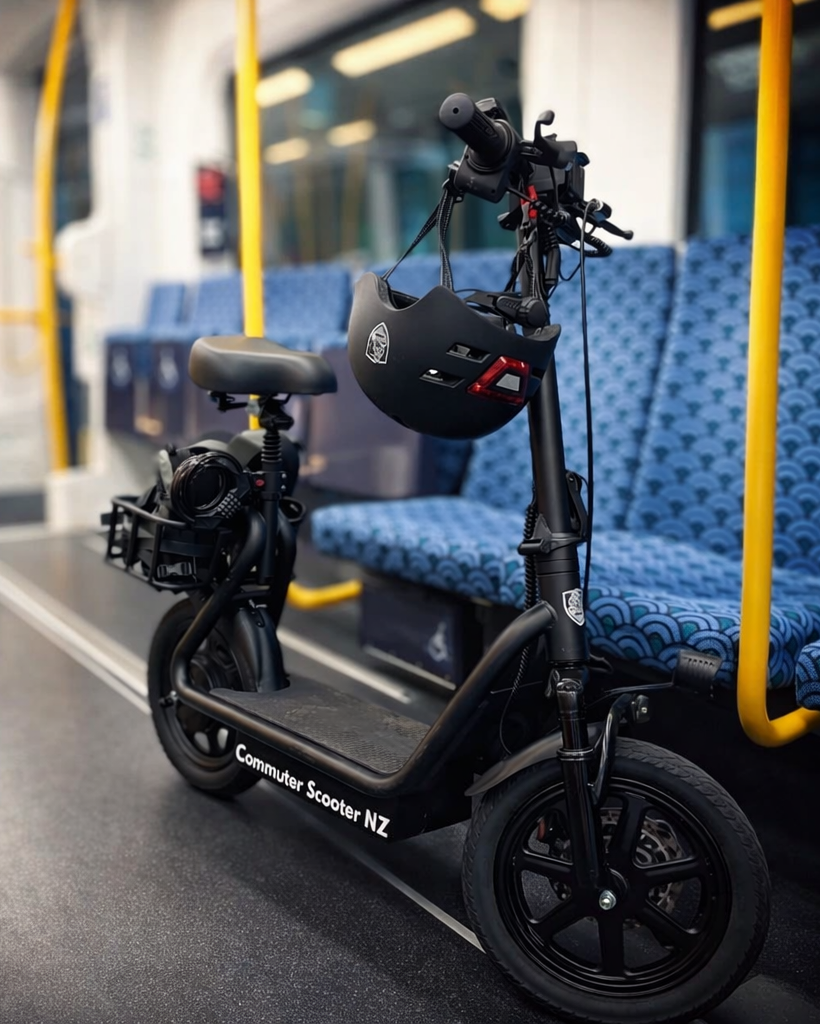 Black seated electric scooter with a helmet on inside a train car with blue seats.